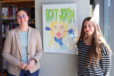 Bild vergr&ouml;&szlig;ern: Die Beigeordnete Lena D&uuml;rphold (links) mit der Gewinnerin Hannah Barlang (rechts) und ihrem pr&auml;mierten Werk zum Thema &raquo;Konsum und S&uuml;chte&laquo;.