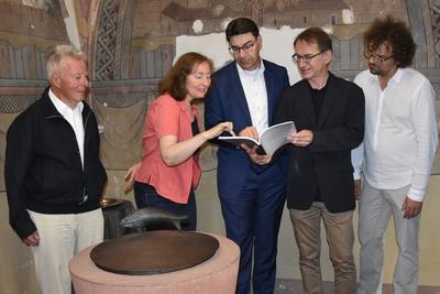 Bild vergr&ouml;&szlig;ern: Spannende Lekt&uuml;re: Dr. Gerald Mathes vom Kirchbauverein der Landauer Stiftskirche, Diplom-Restauratorin Uta-Barbara Riecke, Oberb&uuml;rgermeister Thomas Hirsch, Dekan Volker Janke und Stadtdenkmalpfleger J&ouml;rg Seitz (v.l.n.r.) bl&auml;ttern beim Vor-Ort-Termin im Bericht der Restauratorin zu den historischen Funden in der Taufkapelle der Stiftskirche.