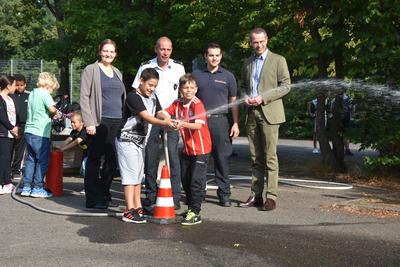Bild vergr&ouml;&szlig;ern: Feuer und Flamme f&uuml;r den Brandschutz: B&uuml;rgermeister und Schuldezernent Dr. Maximilian Ingenthron (r.), Stadtfeuerwehrinspekteur Dirk Hargesheimer (2.v.l.), Barbara Meyer von der TourneeOper Mannheim (l.) und Feuerwehrmann Simon Hargesheimer (2.v.r.) beim Feuerwehrparcours auf dem Schulhof des Max-Slevogt-Gymnasiums.