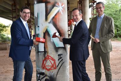 Bild vergr&ouml;&szlig;ern: Oberb&uuml;rgermeister Thomas Hirsch, Verkehrsminister Dr. Volker Wissing und B&uuml;rgermeister Dr. Maximilian Ingenthron (v.l.n.r.) beim symbolischen Hammerschlag zu Beginn des Abrisses und Neubaus der n&ouml;rdlichen Horstbr&uuml;cke in Landau.