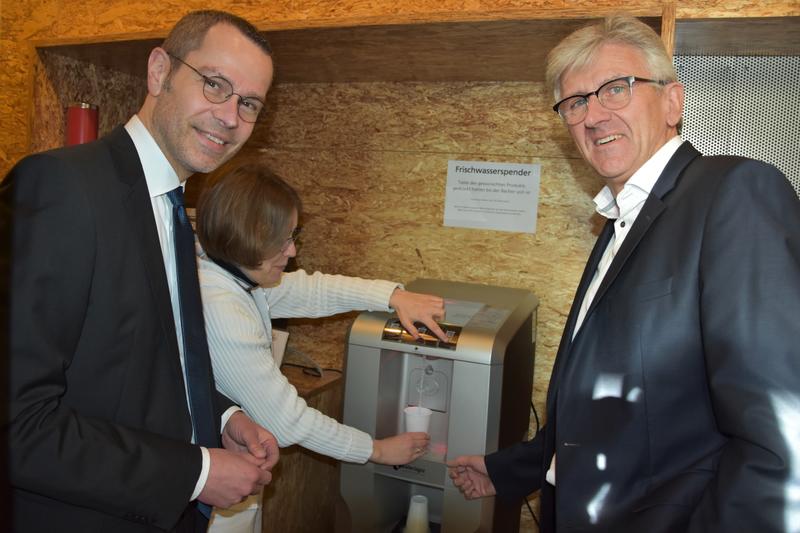 Im Probebetrieb noch mit Plastikbechern, heute mit umweltbewussteren Pappbechern - und auch f&uuml;r die eigene Trinkflasche geeignet: Der neue Frischwasserspender in der Landauer Stadtbibliothek bei der Vorstellung mit B&uuml;rgermeister Dr. Maximilian Ingenthron,
